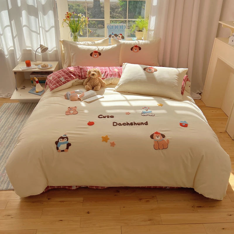 A beige embroidered bedding set featuring cute animal designs like bears and penguins on a bed.