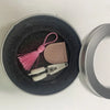 Mini precision sewing scissors with a pink tassel and protective cover resting in a dark bowl.