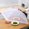 A white foldable mesh insect and fly protection cover is placed over a plate of cooked meat and a plate of green vegetables o