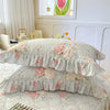 Two floral cotton pillow covers with ruffled edges displayed on a bed.