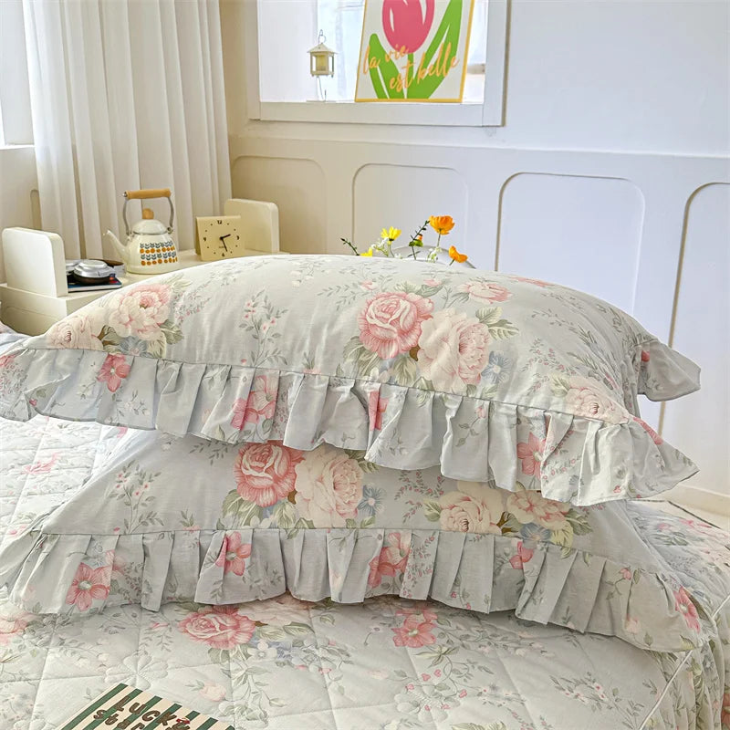 Two floral cotton pillow covers with ruffled edges displayed on a bed.