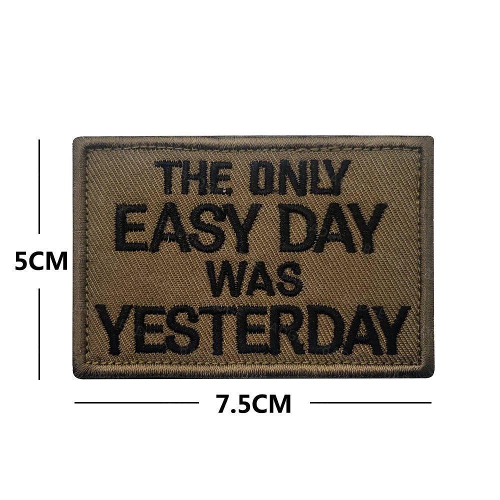 A rectangular brown embroidered patch with black text that reads THE ONLY EASY DAY WAS YESTERDAY