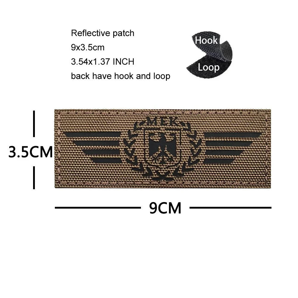 A rectangular brown embroidered patch featuring a black eagle shield design and wings.
