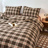 A brown and cream plaid duvet cover set with matching pillows and a plaid throw on a bed.
