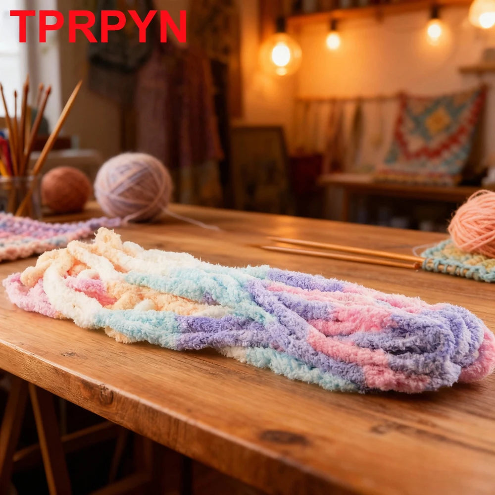 A long piece of hand-woven chunky chenille yarn in multi-colored stripes is displayed on a wooden table.