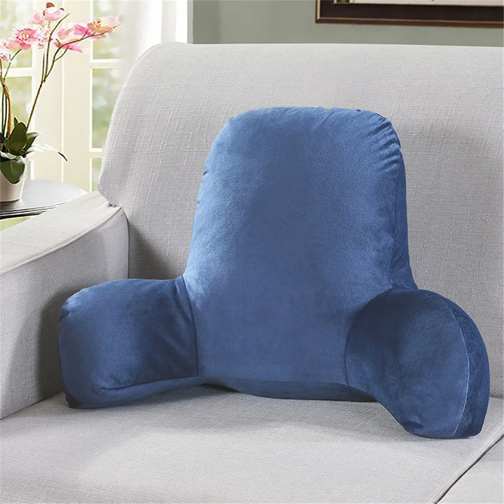 A blue plush lumbar support cushion with arms resting on a light gray sofa.