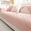 A pink textured sofa cushion cover with a white knitted pillow and a white cup on a light-colored bed.