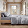A bedroom featuring a wooden bed with gray striped satin bedding set and light wood paneling.