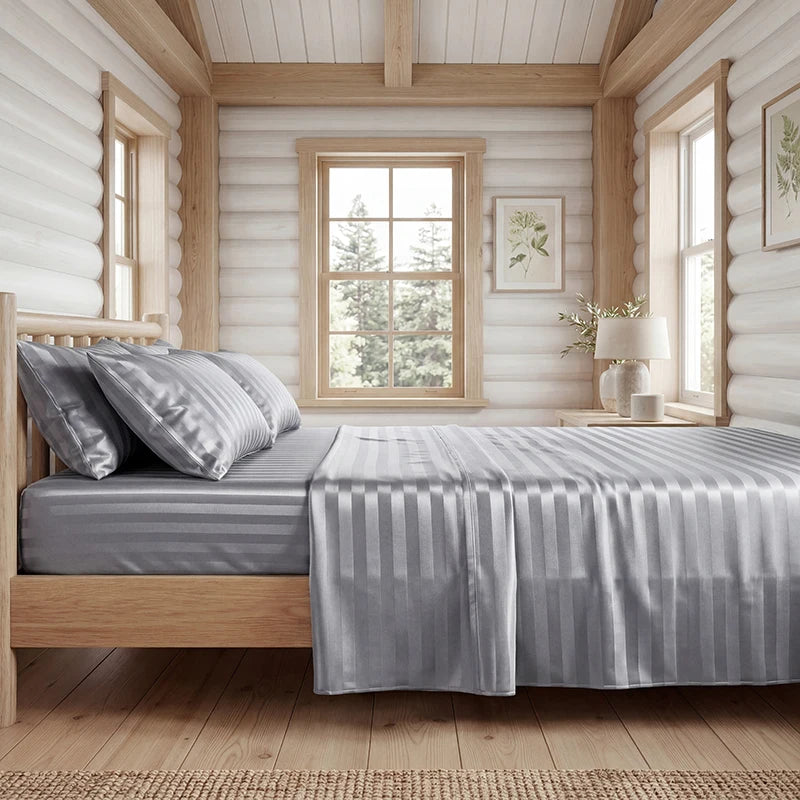 A bedroom featuring a wooden bed with gray striped satin bedding set and light wood paneling.