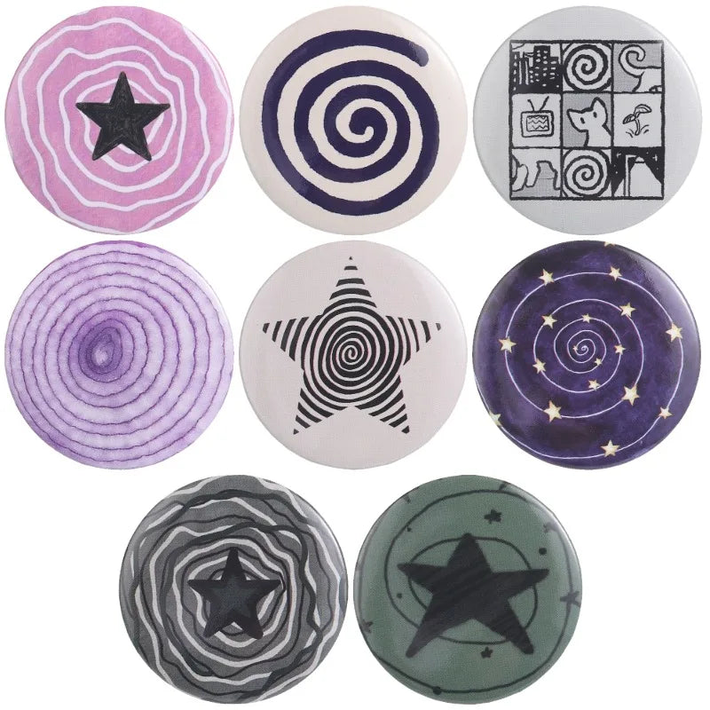A set of nine tinplate pin brooches featuring various designs including stars, spirals, and animals in purple, black, and sil