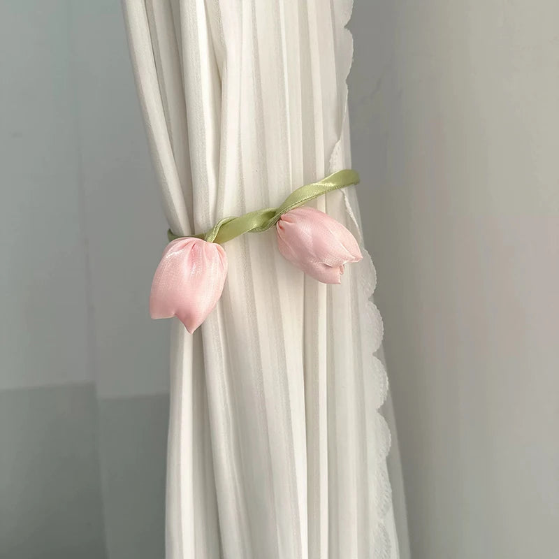 Pink tulip flower curtain tie backs with light green ribbon attached to white sheer fabric.