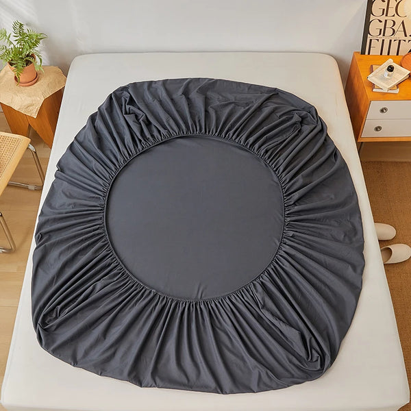 A dark gray fitted sheet is laid out on a white surface.