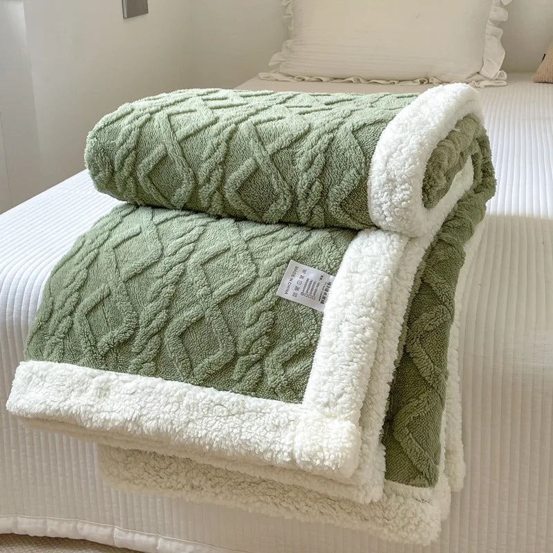 A thick green fleece blanket with white sherpa trim folded on a white bed.