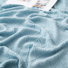 A light blue knitted tassel throw blanket draped and folded on a surface.