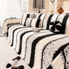A black and white striped jacquard sofa throw draped over a light-colored sofa.