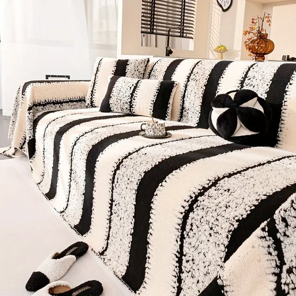A black and white striped jacquard sofa throw draped over a light-colored sofa.