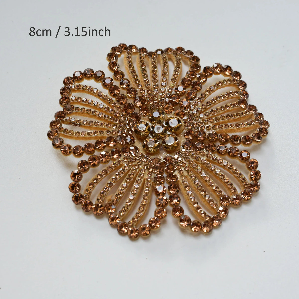 A close-up of a round, textured gold rhinestone flower applique patch for clothing.
