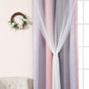 Grey and pink gradient star perforated curtains hanging in a window with a floral wreath on the wall