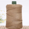 A spool of tan crochet ice rope with a dark green cap resting on a woven mat.