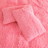 A pink plush duvet cover set lying on a pink fuzzy blanket.