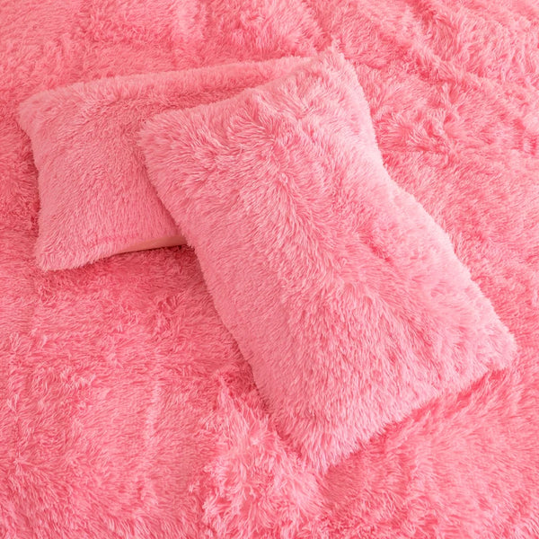 A pink plush duvet cover set lying on a pink fuzzy blanket.