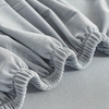 Light gray elastic sofa slipcovers folded and draped on a surface.