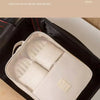 A white portable travel shoe organizer bag is placed inside a black suitcase.