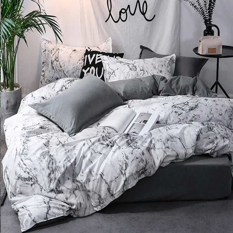 A bedroom setting featuring a white and gray marble patterned duvet cover, pillows, and bedding.