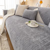 A gray geometric chenille sofa cushion cover with light beige throw and a white cup on the fabric.