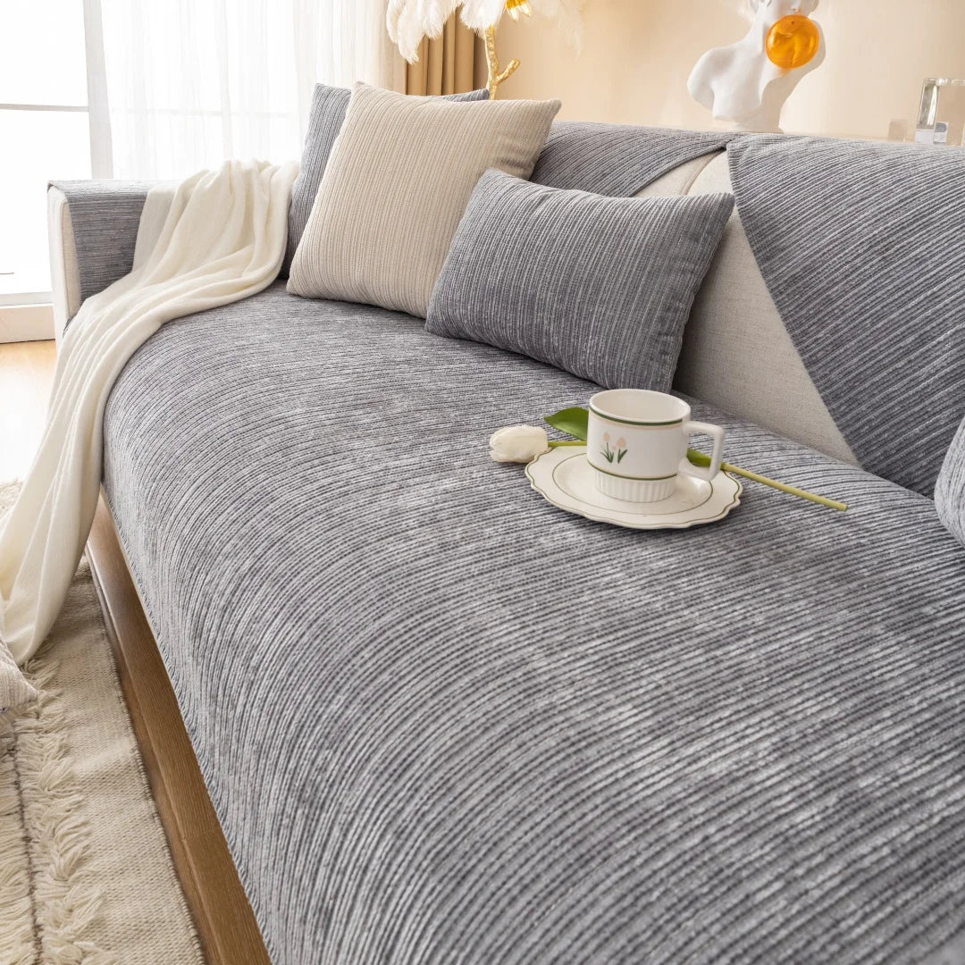 A gray geometric chenille sofa cushion cover with light beige throw and a white cup on the fabric.