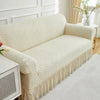 A beige jacquard stretch sofa cover featuring a geometric pattern and a ruffled hem.