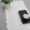 A black rectangular tray holding a white cup rests on a white lace table runner with a plant in a pot.