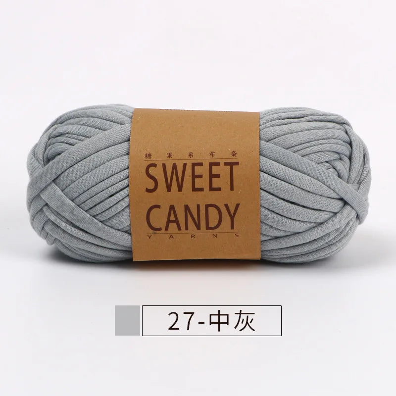 A skein of gray hand-dyed fabric strip yarn labeled Sweet Candy yarns.