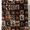 A patchwork flannel throw blanket featuring an orange and black Halloween theme with pumpkins, moons, and bats.