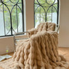 A plush faux fur throw blanket in a beige color draped over a metal chair near a window.