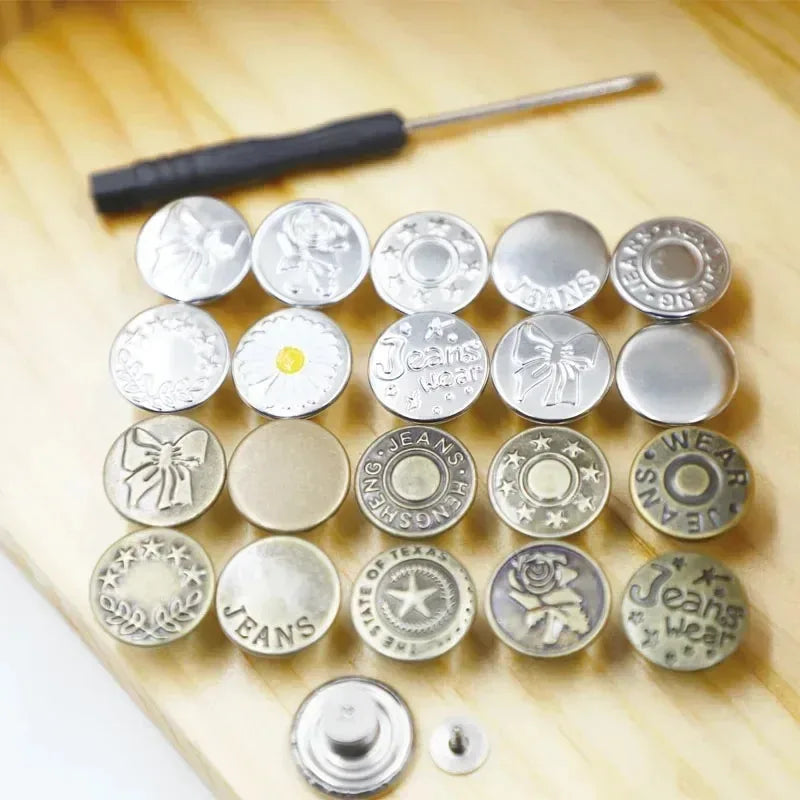 A collection of 30 silver jeans buttons laid out on a wooden surface with a screwdriver nearby.