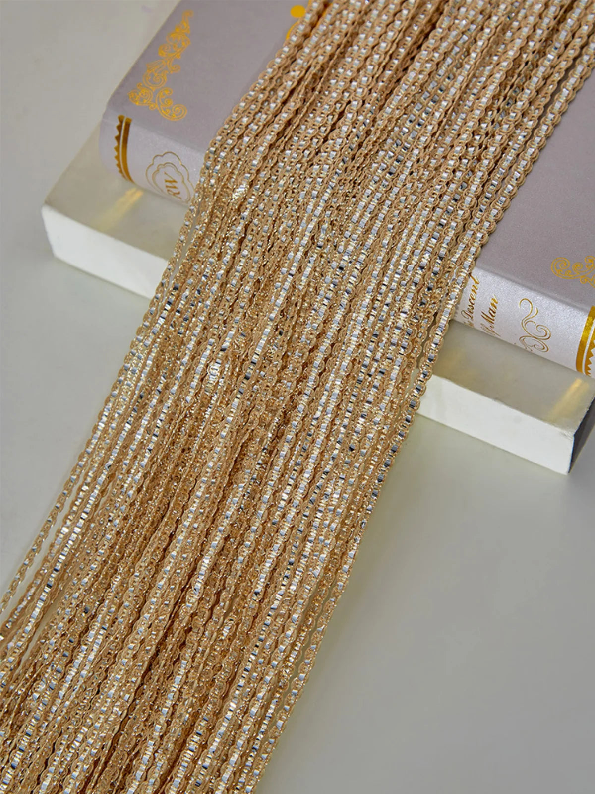 Golden beaded decorative door string curtains displayed next to a book.