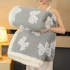 A person is holding a thick gray jacquard lambswool blanket with white embroidered patterns.