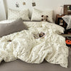 A white duvet cover set with a black polka dot pattern is displayed on a bed, surrounded by pillows and a teddy bear.