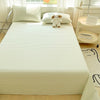 A light green and white checkered organic cotton bedding set featuring a flat sheet, pillowcases, and a stuffed bear on a bed