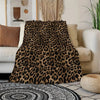 A luxurious leopard print flannel blanket draped over a sofa next to a woven rug.