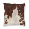 A square cushion cover made of brown and white faux fur cowhide print.