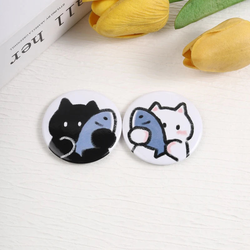 A set of two tinplate pins featuring cute black and gray animal characters, likely themed around music.