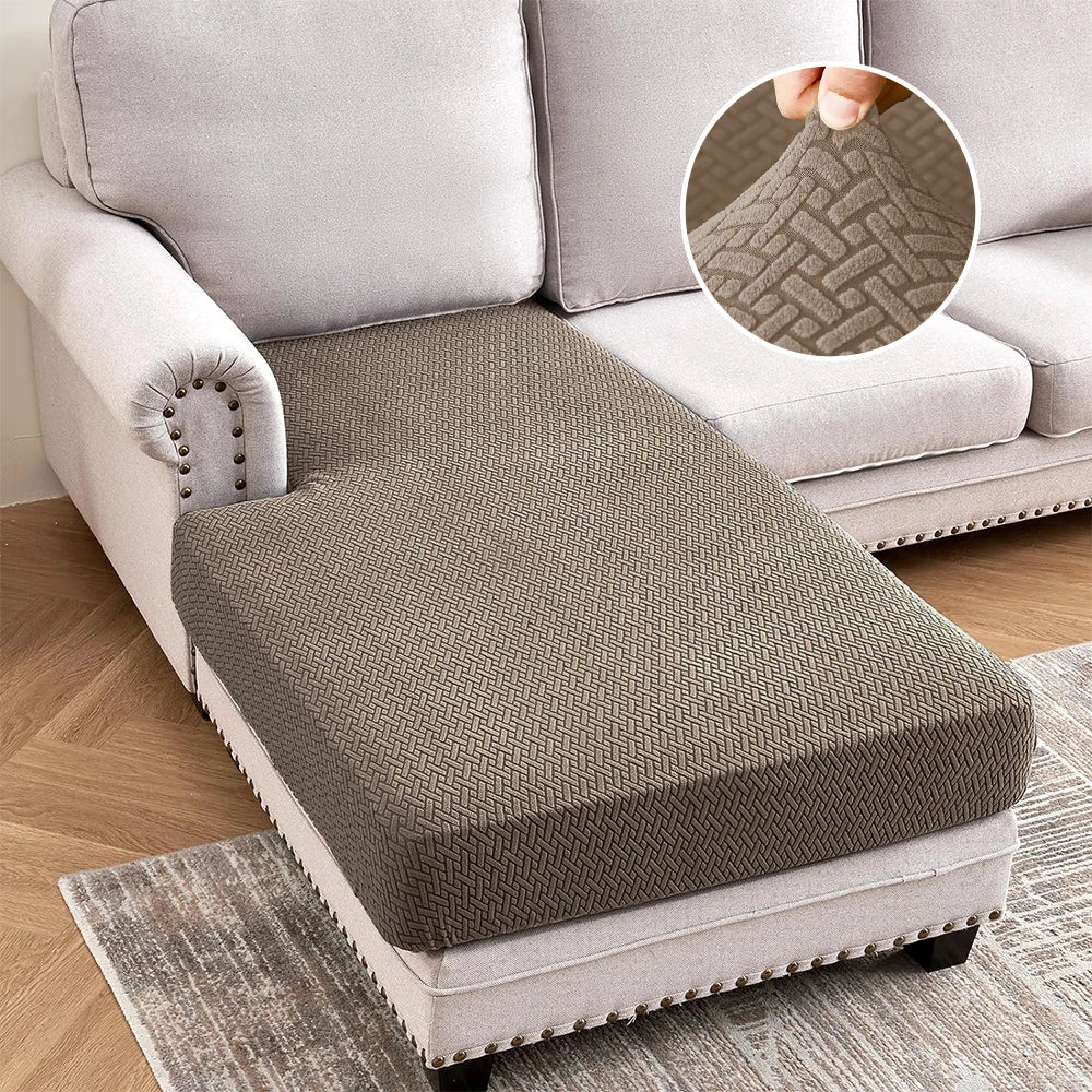 A gray jacquard stretch sofa cushion cover placed on a light-colored rug.