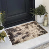 A rectangular faux fur area rug with brown and black mottled patterns placed on a light gray floor.