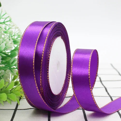 Rolls of purple satin ribbon with gold edges for gift wrapping and crafts