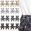 A collection of adjustable bear button pins in gold, silver, and black colors displayed on a denim fabric.