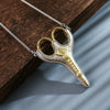 Vintage stainless steel sewing scissors with gold accents displayed on a dark wooden surface.
