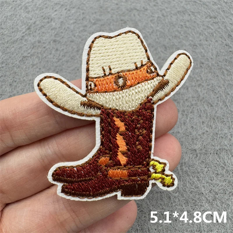 An embroidered iron-on patch of a western cowboy hat and boot in brown and tan colors.