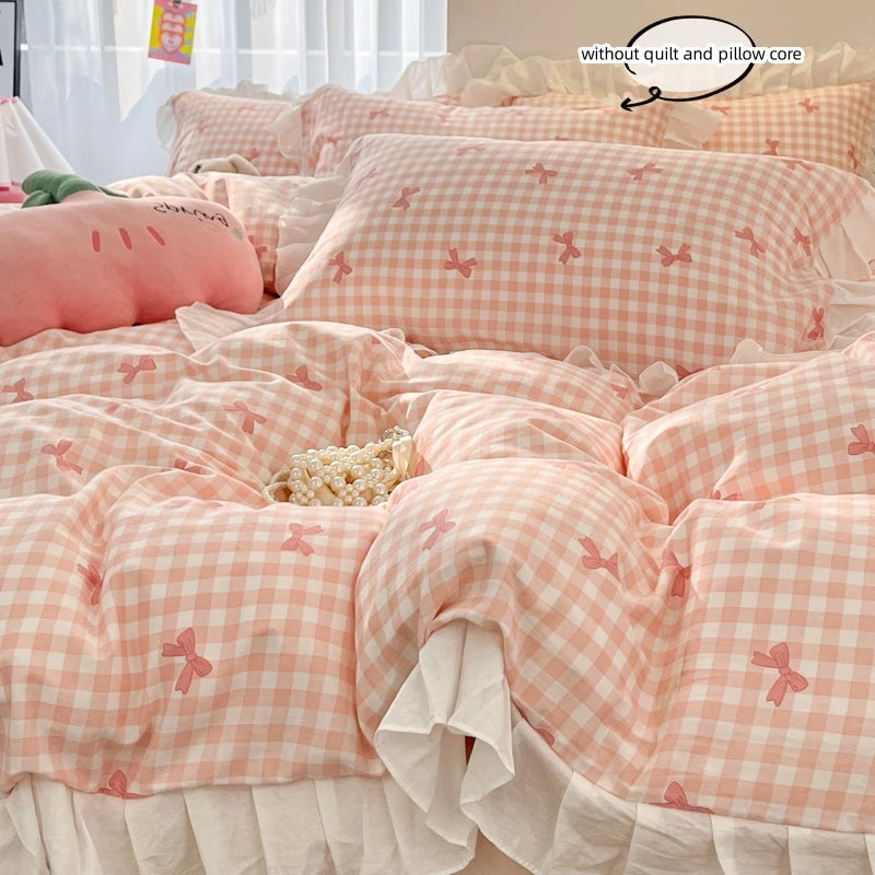 A pink gingham duvet cover set with floral bow accents is displayed on a bed, featuring a quilt and pillow core.